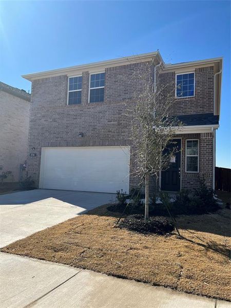 Traditional home featuring concrete driveway, brick siding, and an attached garage