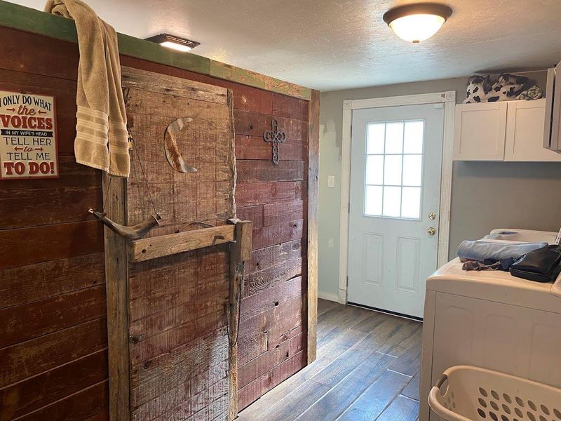 Laundry area featuring a textured ceiling, cabinet space, dark wood-style flooring, and washer and clothes dryer