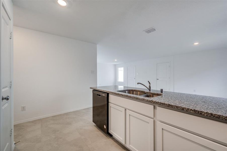 Kitchen with white cabinets, light stone counters, dishwasher, sink, and light tile floors Kitchen with white cabinets, light stone counters, dishwasher, sink, and light tile floors