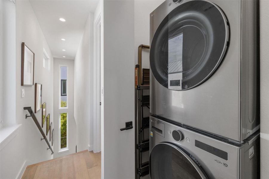 Laundry area featuring stacked washer / dryer, recessed lighting, and light wood-style floors