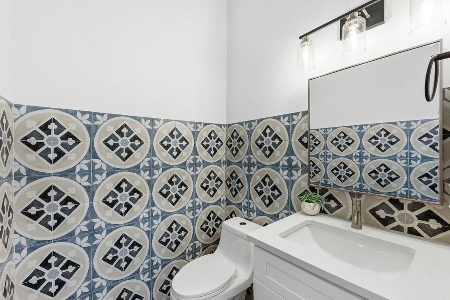 Powder bathroom for guest featuring vanity and tile walls Powder bathroom for guest featuring vanity and tile walls