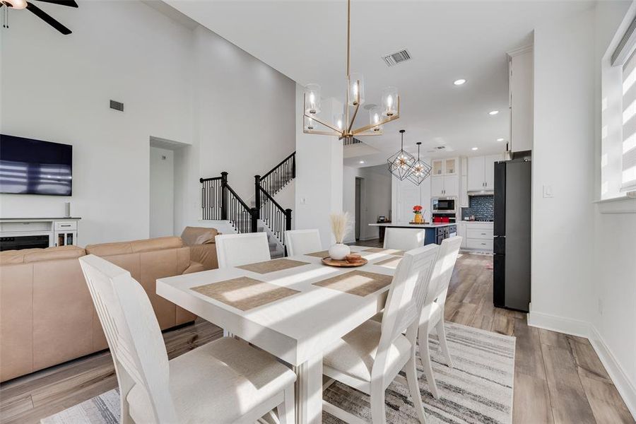 Dining space featuring light wood-style floors, stairway, a chandelier, recessed lighting, and a ceiling fan