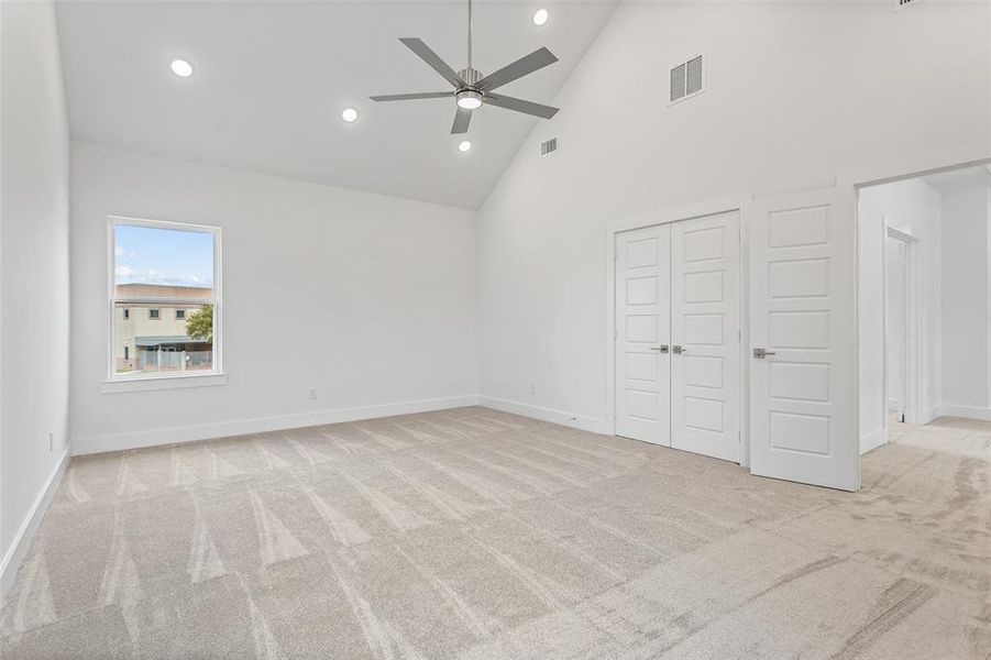 Unfurnished bedroom with ceiling fan, high vaulted ceiling, and light colored carpet