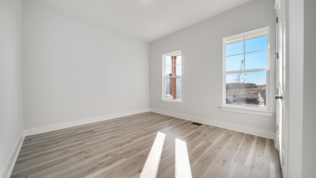Secondary bedroom with hard-surface flooring and large windows