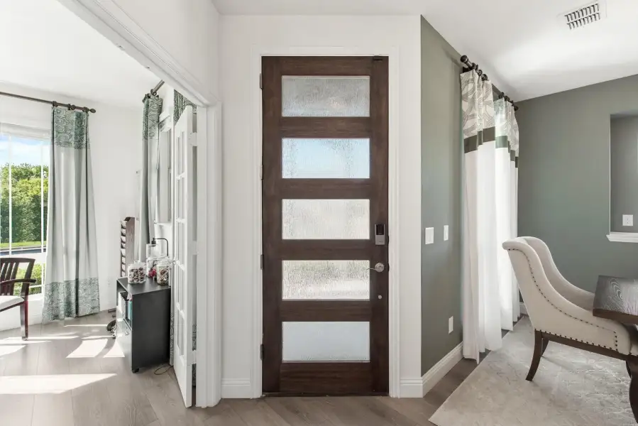 Dark wood interior door with five frosted glass panels in a hallway with gray-green walls and hardwood floors