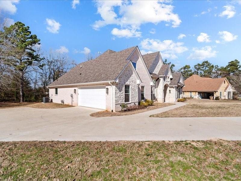 View of front facade featuring stone siding, concrete driveway, and an attached garage