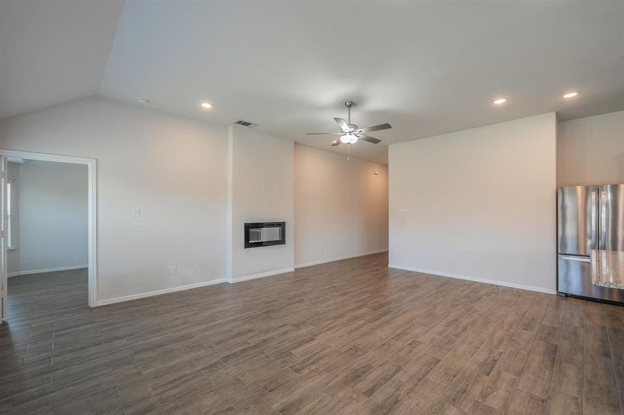 Unfurnished living room with a glass covered fireplace, dark wood-style floors, vaulted ceiling, recessed lighting, and ceiling fan Unfurnished living room with a glass covered fireplace, dark wood-style floors, vaulted ceiling, recessed lighting, and ceiling fan