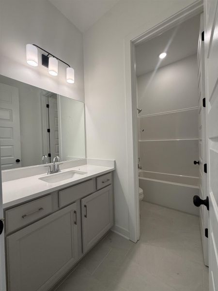Bathroom vanity featuring a light gray cabinet with brushed nickel hardware, a white countertop, and an undermount sink with a chrome faucet