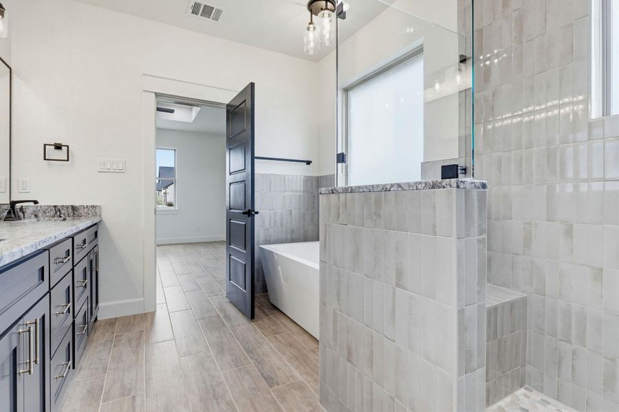 A well-appointed primary bath features a separate tub, a spacious walk-in shower, and a double vanity with stone counters. A well-appointed primary bath features a separate tub, a spacious walk-in shower, and a double vanity with stone counters.
