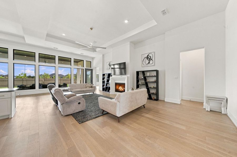 Designed for both relaxing and entertaining, this living room offers seamless connectivity to the backyard through expansive windows. High ceilings and warm wood-look flooring add to the open, airy feel throughout.