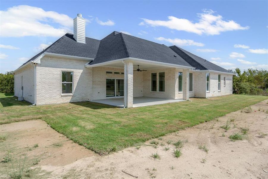 Rear view of property with a patio area, brick siding, a lawn, and a shingled roof Rear view of property with a patio area, brick siding, a lawn, and a shingled roof