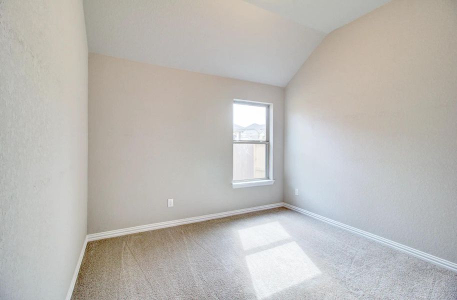 Unfurnished room with vaulted ceiling, carpet floors, and a textured wall Unfurnished room with vaulted ceiling, carpet floors, and a textured wall