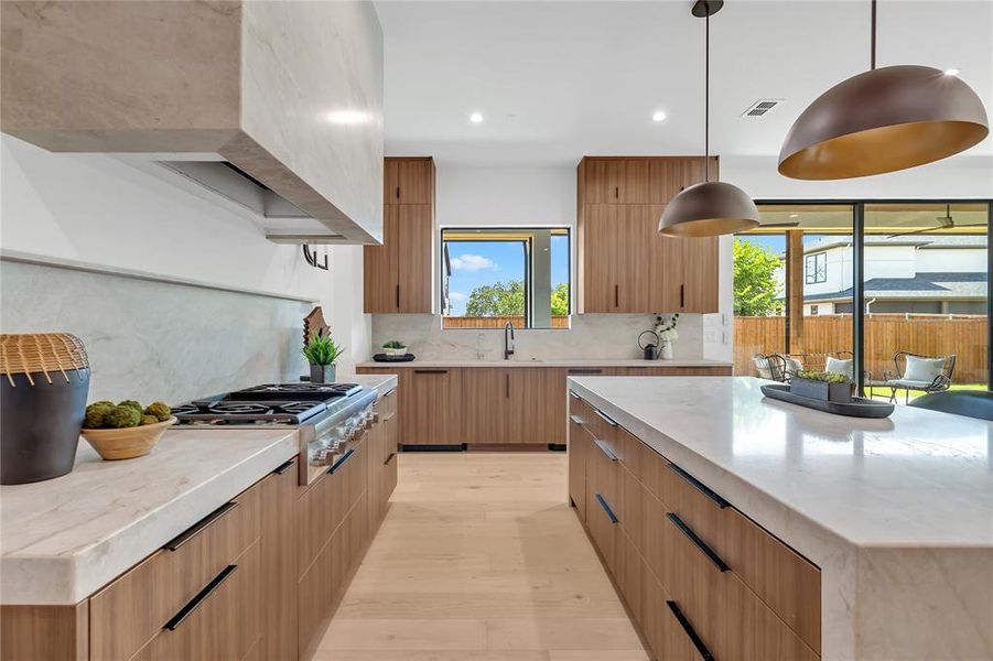 Kitchen with stainless steel gas stovetop, modern cabinets, light wood-type flooring, backsplash, and recessed lighting Kitchen with stainless steel gas stovetop, modern cabinets, light wood-type flooring, backsplash, and recessed lighting