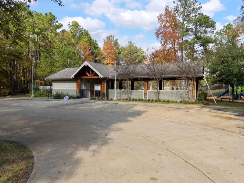 Charming community building with a covered pavilion, nestled amidst trees with a well-maintained exterior and adjacent playground. Ideal for family gatherings and outdoor activities.