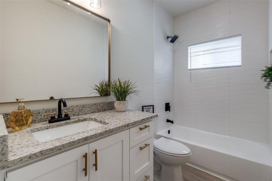 Full bathroom featuring vanity, tiled shower / bath, and toilet