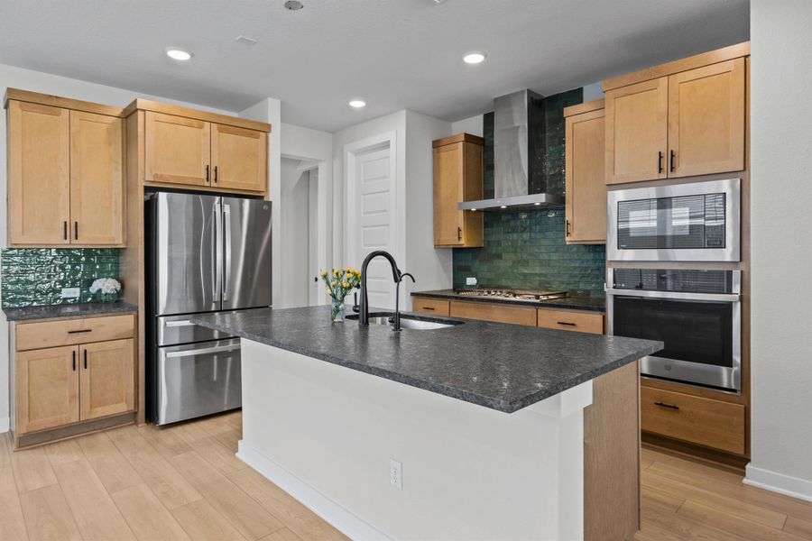Kitchen with stainless steel appliances, tasteful backsplash, light wood finished floors, wall chimney range hood, and recessed lighting