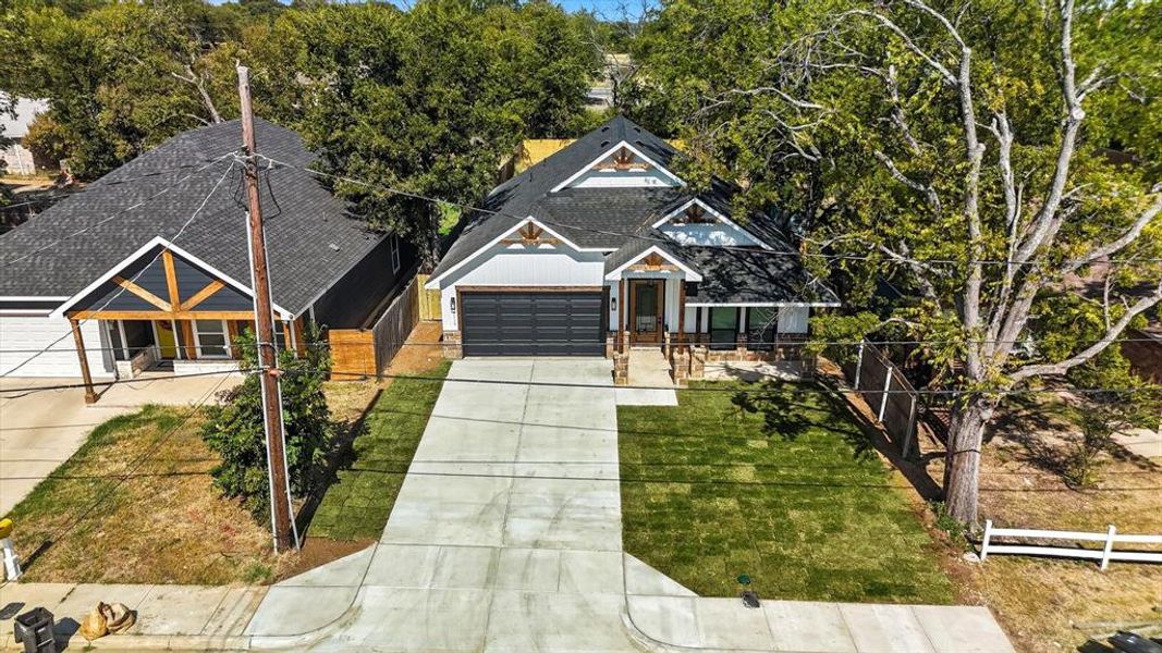 View of front of property with driveway, roof with shingles, and a garage