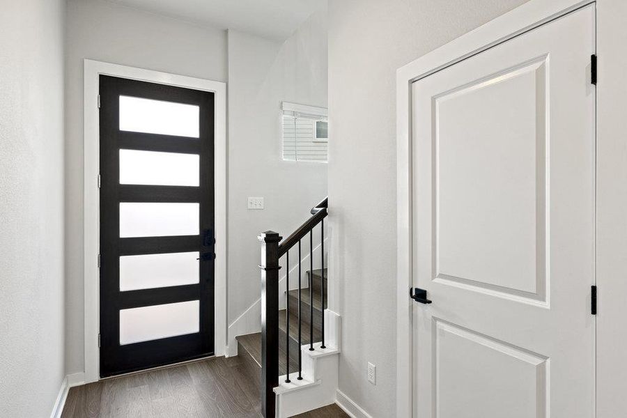 Foyer with dark wood-type flooring and baseboards
