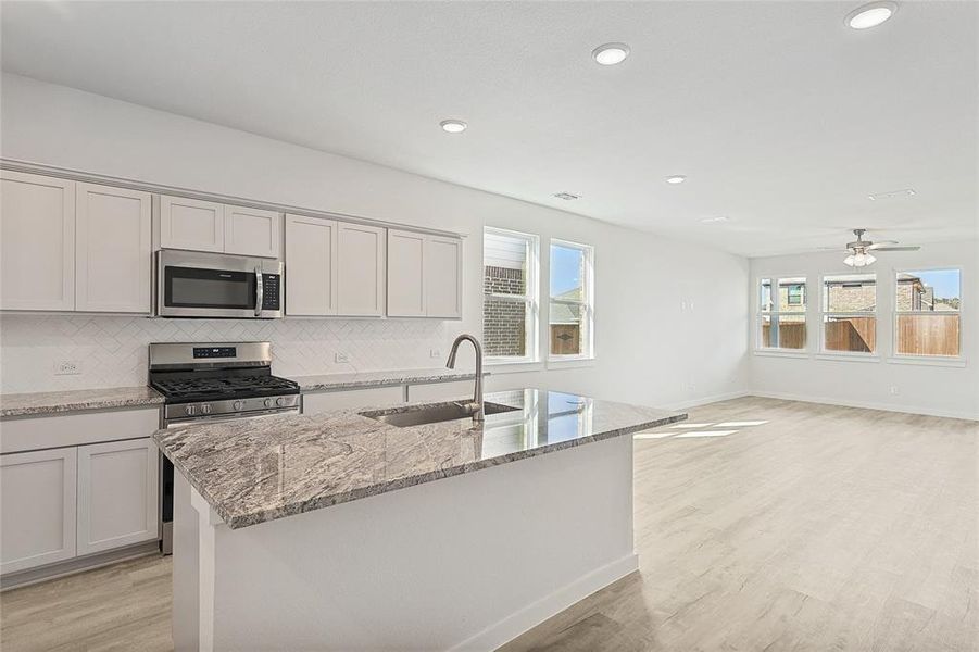 Kitchen featuring a center island with sink, sink, appliances with stainless steel finishes, and light hardwood / wood-style flooring