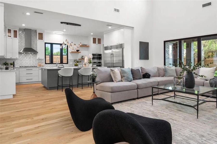 Open-concept living area featuring high ceilings and wood-finish flooring Open-concept living area featuring high ceilings and wood-finish flooring