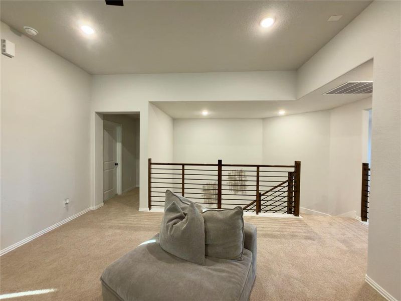 Living area with an upstairs landing, recessed lighting, and light colored carpet