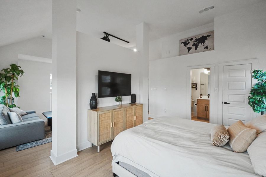 Private garage apartment bedroom suite featuring high ceilings, warm wood flooring, and an open layout that flows into the living area. A well-appointed ensuite bath adds comfort and convenience.