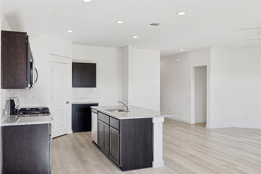 Kitchen with a kitchen island with sink, sink, range with gas stovetop, and light hardwood / wood-style flooring