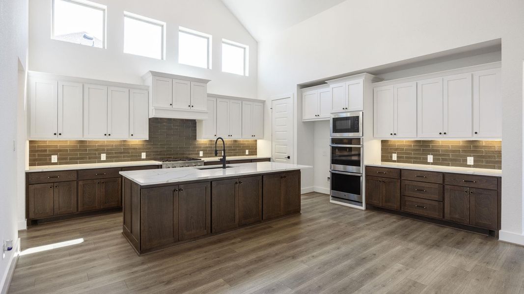 Kitchen featuring dark brown cabinets, tasteful backsplash, white cabinetry, high vaulted ceiling, and a kitchen island with sink Kitchen featuring dark brown cabinets, tasteful backsplash, white cabinetry, high vaulted ceiling, and a kitchen island with sink