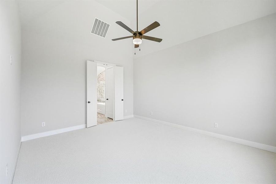 Empty room featuring carpet flooring, high vaulted ceiling, and ceiling fan