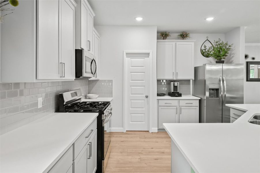 Bright kitchen with white cabinetry, subway tile backsplash, and generous counter space.