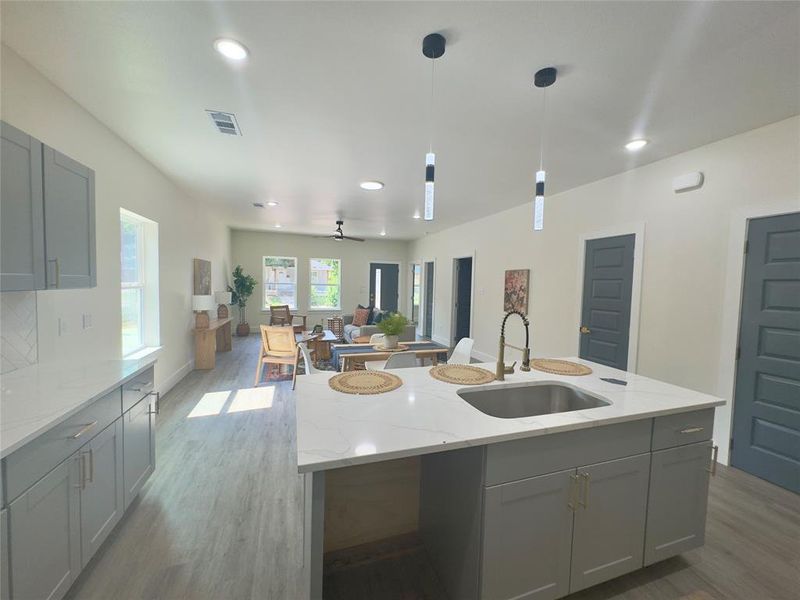 Kitchen with decorative light fixtures, sink, an island with sink, and hardwood / wood-style floors