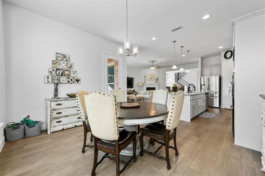 Dining area with light wood-type flooring, sink, and ceiling fan with notable chandelier