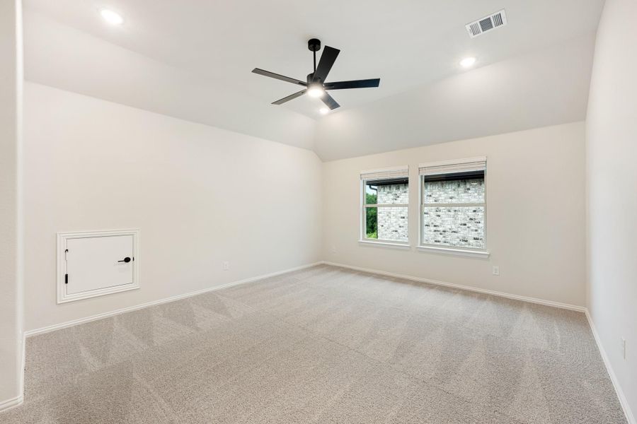 Empty bedroom with vaulted ceiling, black ceiling fan, carpet flooring, and two windows Empty bedroom with vaulted ceiling, black ceiling fan, carpet flooring, and two windows