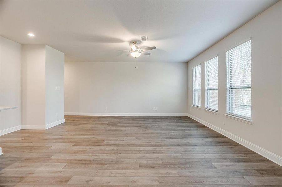 Empty room with light wood-type flooring, baseboards, visible vents, and a ceiling fan