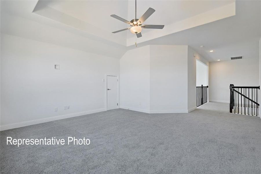 Carpeted room featuring a tray ceiling with a ceiling fan