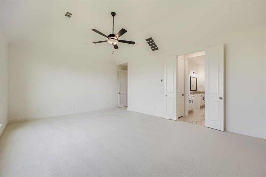 Unfurnished bedroom featuring light colored carpet, high vaulted ceiling, ceiling fan, and connected bathroom