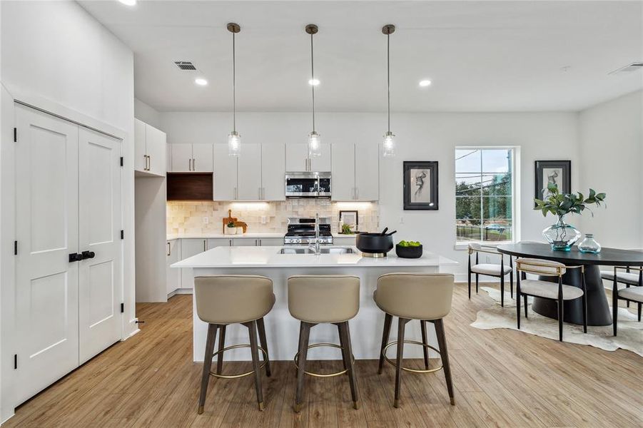 Modern kitchen featuring a sleek island with seating, under stylish pendant lighting, perfect for entertaining and meal prep.