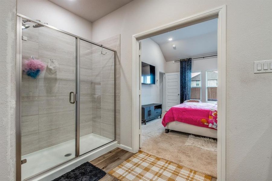 Full bathroom featuring ensuite bathroom, a shower stall, lofted ceiling, light wood-style flooring, and recessed lighting