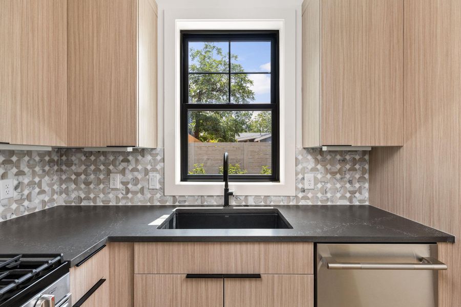 Kitchen featuring light brown cabinetry, appliances with stainless steel finishes, backsplash, and dark stone counters Kitchen featuring light brown cabinetry, appliances with stainless steel finishes, backsplash, and dark stone counters