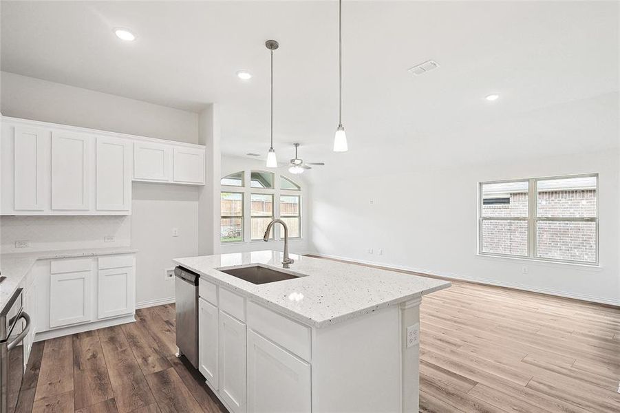 Kitchen with ceiling fan, a kitchen island with sink, hardwood / wood-style flooring, and white cabinets