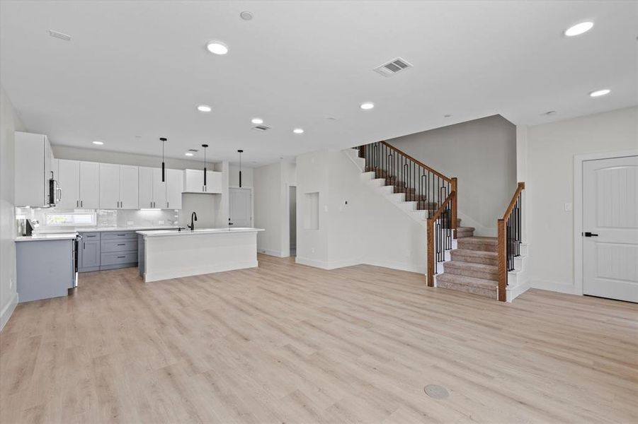 Unfurnished living room with stairway, light wood-style flooring, and recessed lighting