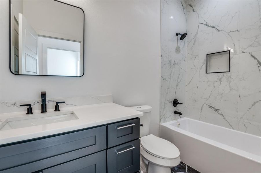 Full bathroom with toilet, tiled shower / bath combo, and vanity