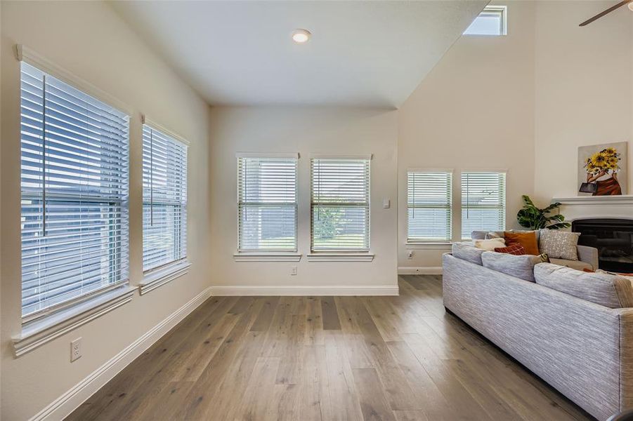 Living room featuring a glass covered fireplace, hardwood / wood-style floors, a high ceiling, recessed lighting, and a ceiling fan