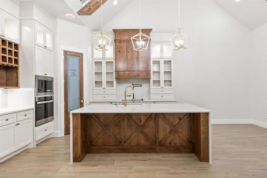 Contemporary kitchen featuring a large wood-paneled island with a white countertop, complemented by white cabinetry and a wood range hood Contemporary kitchen featuring a large wood-paneled island with a white countertop, complemented by white cabinetry and a wood range hood