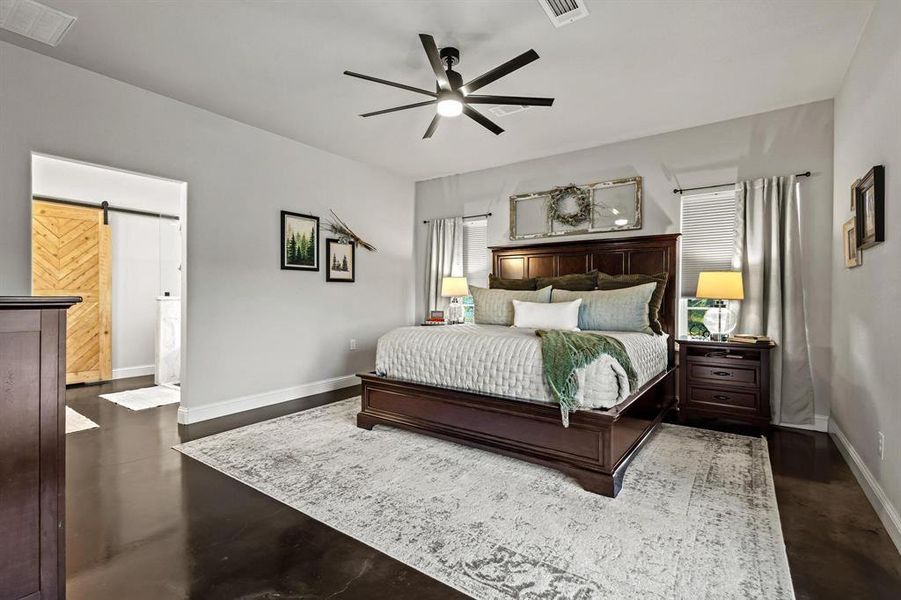 Bedroom featuring a barn door, a ceiling fan, and connected bathroom Bedroom featuring a barn door, a ceiling fan, and connected bathroom