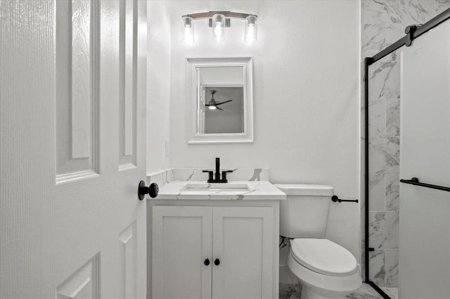 Bathroom featuring vanity, toilet, and tiled shower