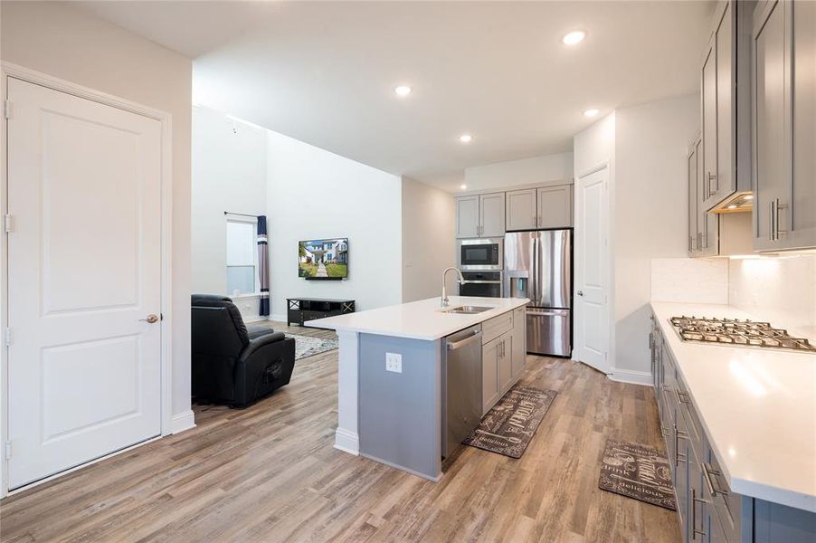 Wood look vinyl flooring extends into the large kitchen which is open to the 
 living area.