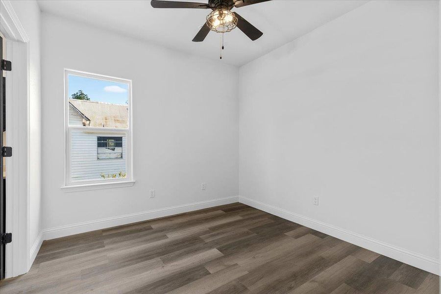Rich wood plank flooring and crisp white walls anchor this versatile secondary bedroom space. Rich wood plank flooring and crisp white walls anchor this versatile secondary bedroom space.