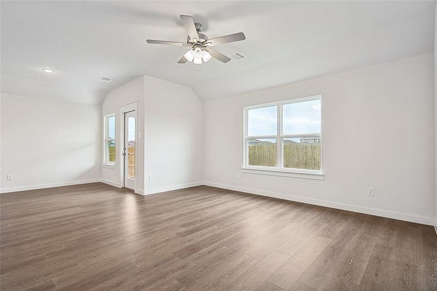 Empty room with vaulted ceiling, dark hardwood / wood-style flooring, and ceiling fan