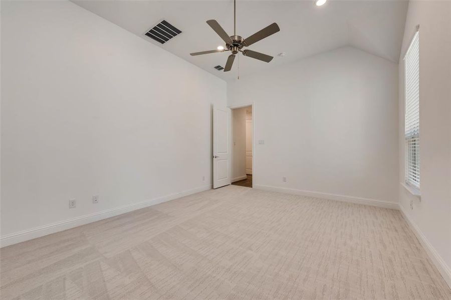 Carpeted empty room with high vaulted ceiling and ceiling fan